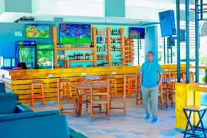 a man standing in a restaurant with tables and chairs at KBH by Royal Village in Singida