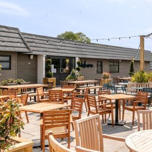 an outdoor patio with wooden tables and chairs at Daisy's Haven - Endless Pool, Tennis, Sky TV in Port Carlisle