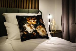 a bed with a flower pillow on it at Boardinghaus Grünefeld W4 I by WOOON I Küche I Smart TV I P I Rainshower in Mettingen