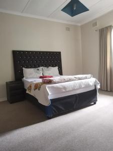 une chambre avec un grand lit avec une tête de lit noire dans l'établissement J & J Paradise Guest House, à Pietermaritzburg