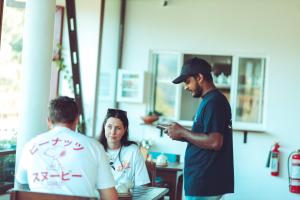 a man looking at his cell phone while two people are working at Ella Soul Resort in Ella
