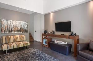 a living room with a couch and a flat screen tv at Vallegrande Nature Resort by Geocharme in Cefalù