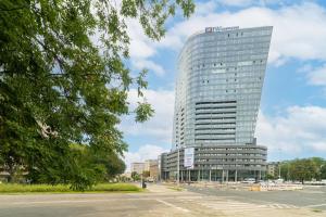 un edificio de cristal alto con un estacionamiento delante de él en MARGI Melia Apartament BASEN POOL SAUNA, en Szczecin
