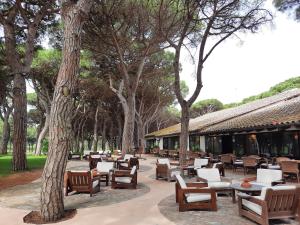 a patio with tables and chairs and trees at Apartamentos Golf Mar I & II by La Costa Resort in Pals