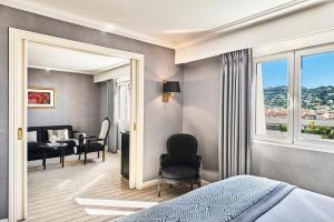 a bedroom with a bed and a living room at Hôtel Barrière Le Majestic Cannes in Cannes
