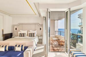 a bedroom with a bed and a balcony with the ocean at Hôtel Barrière Le Majestic Cannes in Cannes