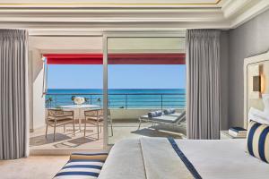 a bedroom with a bed and a view of the ocean at Hôtel Barrière Le Majestic Cannes in Cannes