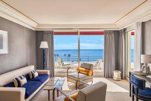 a living room with a couch and a view of the ocean at Hôtel Barrière Le Majestic Cannes in Cannes