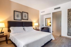 a bedroom with a large white bed with two lamps at Vallegrande Nature Resort by Geocharme in Cefalù