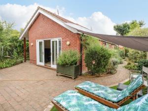 a brick house with a patio and some chairs at Swift Host - 3 Bedrooms - 2 Living Areas - Cinema Room - Garden - Family Pet Friendly - Norfolk Broads - Parking in Brundall