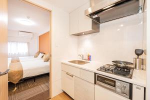 a kitchen with a stove and a bed in a room at 鵜の木民宿101号室鵜の木駅から徒歩4分とても便利の場所 in Tokyo