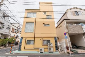 a yellow building with two chairs in front of it at 鵜の木民宿101号室鵜の木駅から徒歩4分とても便利の場所 in Tokyo