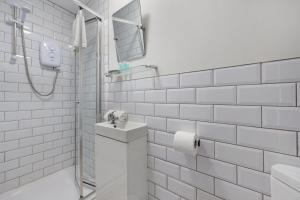 a white tiled bathroom with a sink and a shower at Burnand House - Air Host & Stay - Sleeps 9 in Liverpool +27 photos