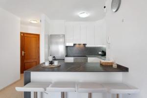 a kitchen with white cabinets and a counter with white stools at Apartamento Rincon Tropical in Candelaria