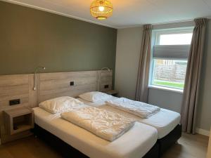 a bedroom with a large bed with white sheets at State Klaver Vier in Hollum