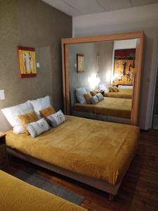 2 Betten in einem Hotelzimmer mit großem Spiegel in der Unterkunft Gîte La Rose des Alpes à Serres, 3 chambres, capacité 2 à 8 personnes, Cuisine, Terrasse, Parking et Garage in Serres