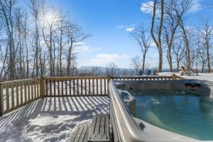 a hot tub on a deck in the snow at Wolf Ridge Lodge in Boone