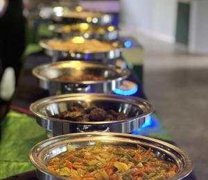 a row of metal pans filled with food on a stove at Sisiliyana Stone Resort in Gonapola