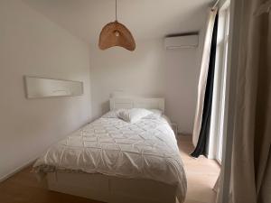 a bedroom with a white bed and a window at Petit paradis perché au coeur de Nice in Nice