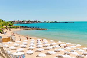 a beach with white umbrellas and people in the water at Nessebar, Studio,South Beach, Larisa in Nesebar