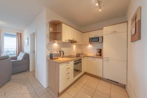 a kitchen with white cabinets and a couch in a room at Gartendeck 501 in Rechlin +10 photos