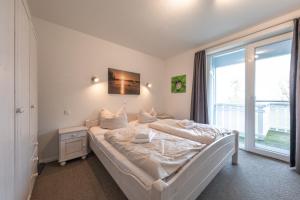 a bedroom with a white bed with a window at Kapitänsdeck 534 in Rechlin