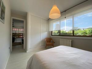 a bedroom with a white bed and a window at Housingcoruña Apartamento Playa Miño 01 in Miño