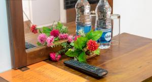 a remote control and flowers on a table with a mirror at Sisiliyana Stone Resort in Gonapola