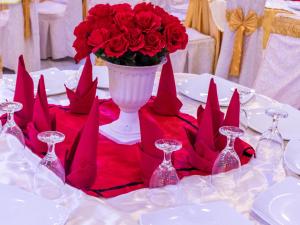 a table with a vase of red roses and wine glasses at Sisiliyana Stone Resort in Gonapola