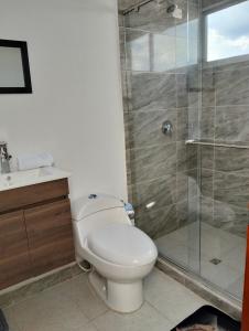 a bathroom with a toilet and a glass shower at Villa Graciela II in Paipa