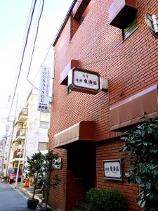 een bakstenen gebouw met borden aan de zijkant bij Asakusa Ryokan Toukaisou in Tokyo