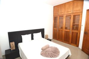 a bedroom with a white bed with a wooden cabinet at Rinconada del Mar APTS in Playa del Carmen +29 photos