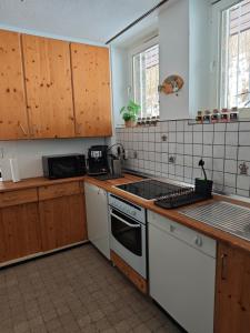 eine Küche mit weißen Geräten und Holzschränken in der Unterkunft Wohlfühloase Schleiden Haus Talblick mit Whirlpool Kamin Aussicht 10 Personen in Schleiden