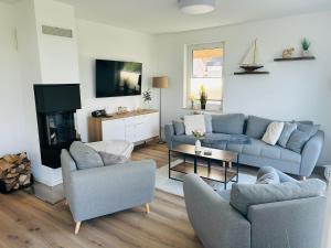 a living room with two couches and a tv at Reetdach-Ferienhaus "ANNI" mit direktem Meerblick, Sauna und Kamin in Pepelow