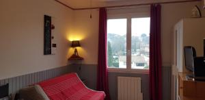 une pièce avec une fenêtre avec des rideaux rouges et un canapé dans l'établissement Studio Albizia Lamalou les Bains, à Lamalou-les-Bains