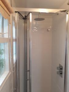 a shower with a glass door in a bathroom at Maypole Cottages No 10 Broad Street Padstow in Padstow