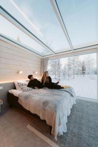 a man and woman laying on a bed in a room with a window at Northern Lights Ranch in Levi