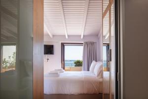 a bedroom with a large bed with a window at Chryssi Seafront Living, 03 Suite, right on the beach in Rethymno! in Rethymno Town