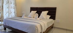 a bed with white blankets and swans on it at Mountain river farm resort in Agali