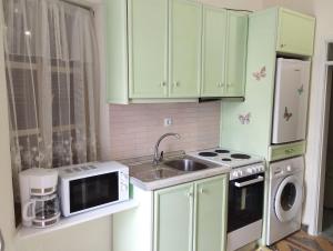 a kitchen with green cabinets and a sink and a microwave at Kyramarias Village house in Malona Village