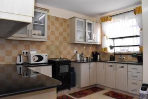 a kitchen with white cabinets and a black stove at Riverside Spacious Haven in Nairobi