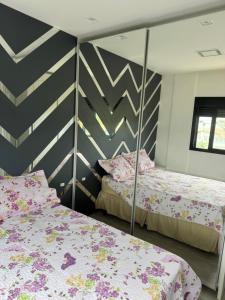 a bedroom with two beds and a striped wall at Suíte privada Mariscal in Bombinhas