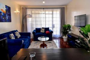 a living room with a blue couch and a table at Riverside Spacious Haven in Nairobi