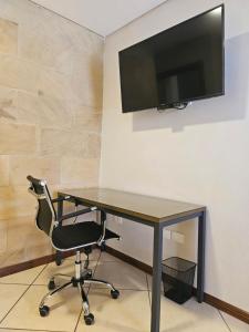 a desk with a chair and a television on a wall at Casa Garay Hotel 658 in Asuncion