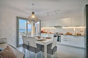 een witte keuken met een eettafel en stoelen bij Empire Luxury Villas in Santa Maria