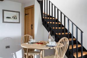 Un comedor con una mesa y una escalera. en Shepherd's Cottage, en Usk