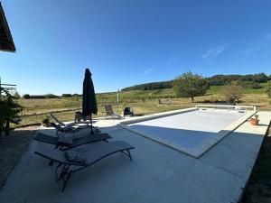 a patio with two chairs and an umbrella and a pool at Les Cabrolles in Saint-Philippe-du-Seignal