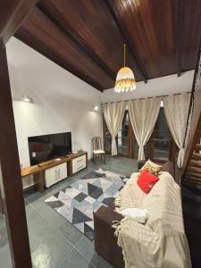 a living room with a couch and a flat screen tv at Casa Azul in Barra de Guaratiba