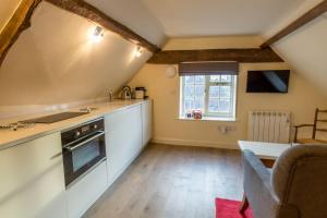 une cuisine avec des armoires blanches, une table et une fenêtre dans l'établissement Minster Loft, à York