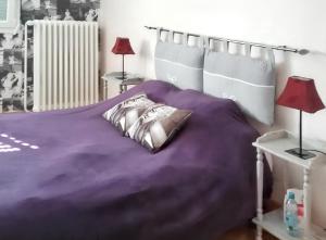 a bed with a purple comforter and two lamps at Maison charmante à La Flèche avec jardin et parking privé in La Flèche